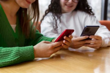 Duas mulheres segurando seus celulares enquanto acessam informações, representando a praticidade de consultar o saldo do FGTS diretamente pelo celular.
