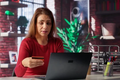 Mulher utilizando computador e cartão cidadão para checar informações do FGTS de forma online, representando a verificação dos depósitos trabalhistas.